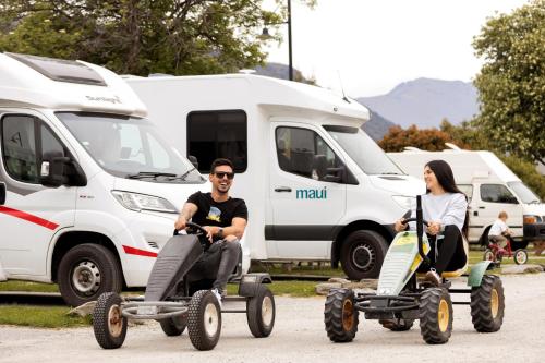 a man and a woman riding onicycles in front of vans at Queenstown Top 10 Holiday Park in Queenstown