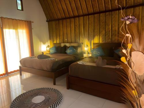 a bedroom with two beds and a large window at Meket Bungalows in Nusa Penida