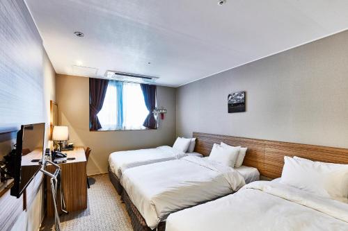 a hotel room with two beds and a television at Golden Harbor Hotel Pyeongtaek in Pyeongtaek