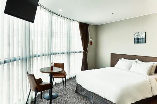 a hotel room with a bed and a table at Golden Harbor Hotel Pyeongtaek in Pyeongtaek