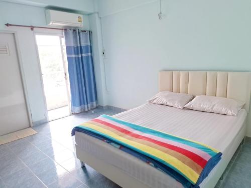 a bed with a rainbow blanket on it in a room at พฤกษาเพลสอยุธยา in Ban Han Tra Fang Nua