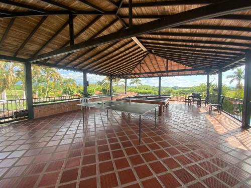 a pavilion with tables and chairs on a tiled floor at FINCA HOTEL LAS CABAÑAS DEL Parque in Pueblo Tapao