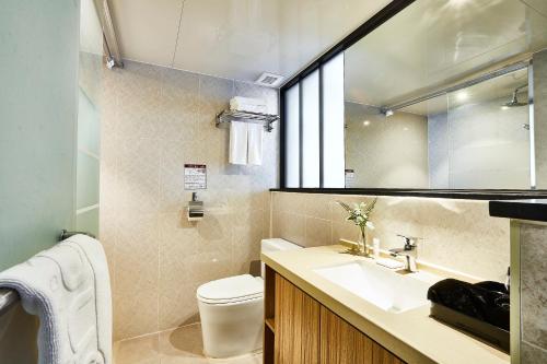 a bathroom with a sink and a toilet and a mirror at Golden Harbor Hotel Pyeongtaek in Pyeongtaek