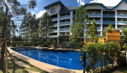 a hotel with a swimming pool in front of a building at Studio Unit at Pine Suites Tagaytay in Tagaytay