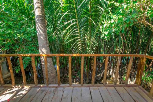 a wooden deck with a tree in front of a forest at Nary Garden in Kampot