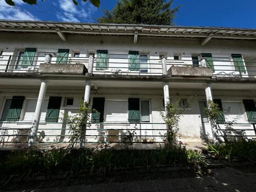 un vieux bâtiment blanc avec des fenêtres vertes à volets dans l'établissement Studio avec jardin, balcon, WIFI et parking près des Thermes - FR-1-541-117, à La Roche-Posay