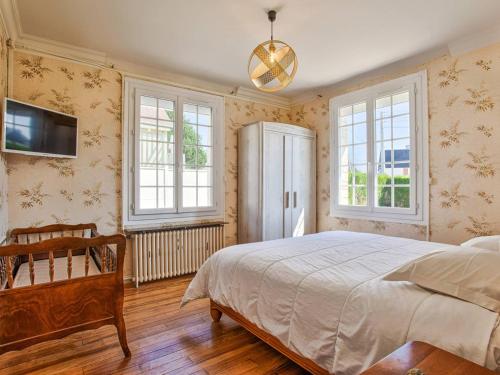 une chambre avec un lit, une télévision et des fenêtres dans l'établissement Maison rétro avec jardin et 5 chambres à Merville-Franceville-Plage - FR-1-788-34, à Merville-Franceville-Plage