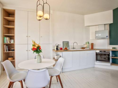 une cuisine avec une table, des chaises et un vase de fleurs dans l'établissement Superbe appartement rénové à Cabourg, face à la mer pour 2 - FR-1-788-33, à Cabourg