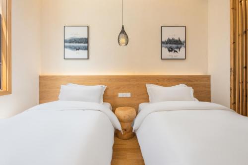 two beds in a room with white sheets at Yunshan Villa in Huangshan Scenic Area