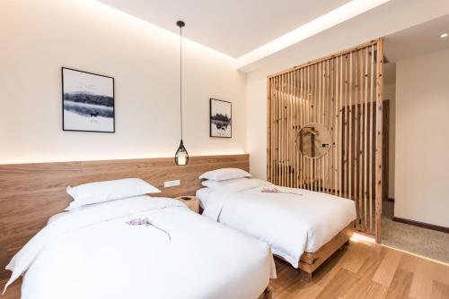 two beds in a room with white sheets at Yunshan Villa in Huangshan Scenic Area