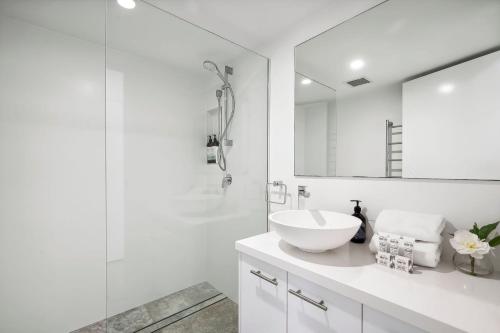 a white bathroom with a sink and a mirror at Unit 8 'The Rocks' in Coolum Beach