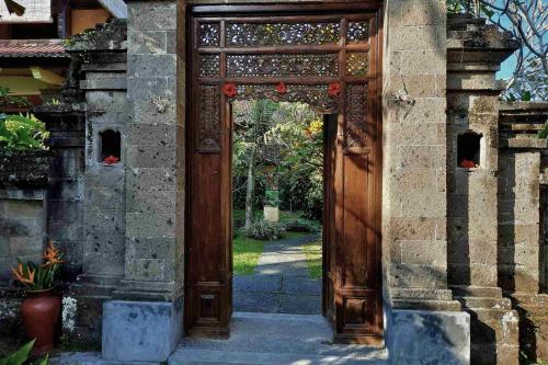 an entrance to a building with a wooden door at Gitali 1 BR Superior Garden View ZN244 in Ubud