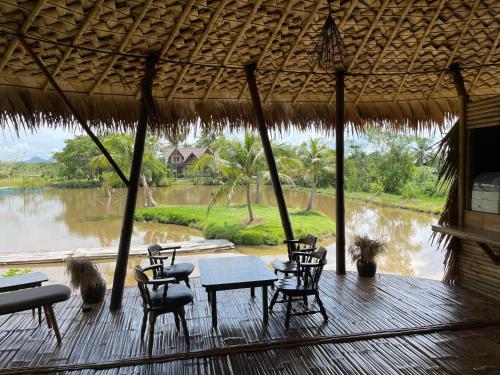 a porch with chairs and tables and a view of a river at Villa Baan Pak Pra in Ban Pak Pra (1)
