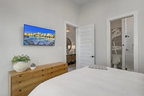 a white bedroom with a bed and a tv on the wall at Keepin' It Reel 234 LAK in Port Aransas