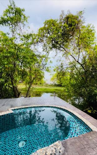 a swimming pool in a garden with trees in the background at Villa Baan Pak Pra in Ban Pak Pra (1)