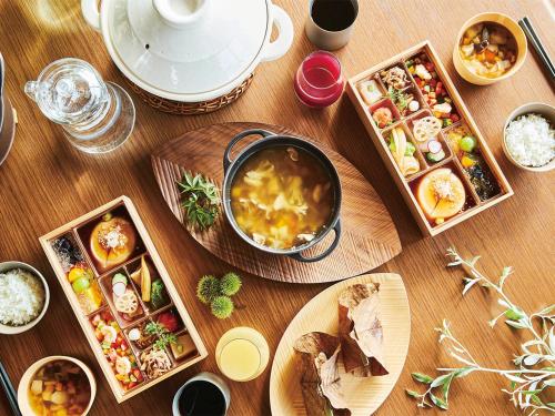 a wooden table with dishes of food on it at Glamdy style hotel suite 山ノ麓 in Karuizawa
