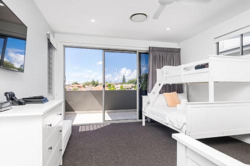 a bedroom with white bunk beds and a window at Ray of Sunshine in Gold Coast