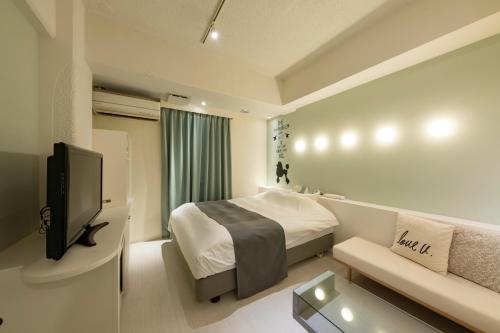 a hotel room with a bed and a tv at Hotel Eldia Modern Sendai -Adult Only in Ayashi