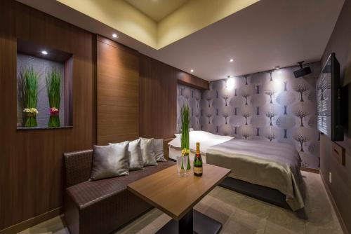 a bedroom with a bed and a table with bottles of wine at Hotel Eldia Modern Sendai -Adult Only in Ayashi