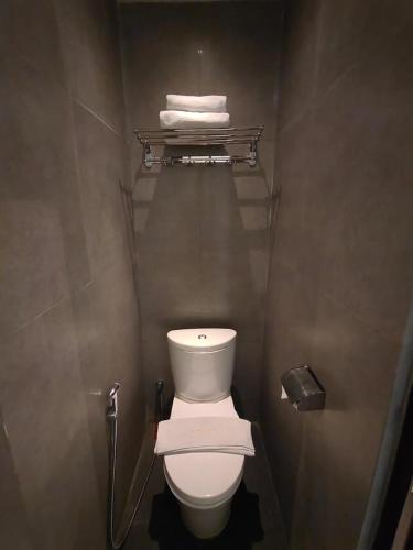 a bathroom with a white toilet and towels at Sweet Garden Guest House in Malang