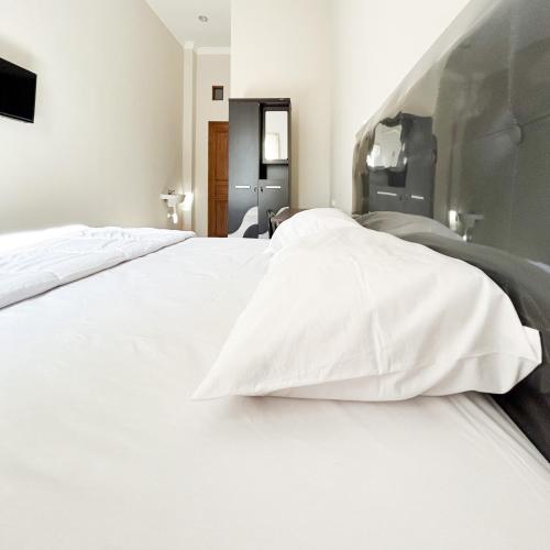 a large white bed with white pillows on it at Queen Belt Mitra Reddoorz in Balong