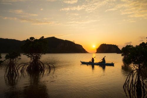 two people in a boat on a lake at sunset at Iriomote Hotel by Hoshino Resorts in Taketomi