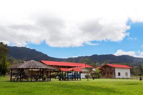 a group of buildings with red roofs on a grass field at Hotel Santa M la Cocha in Pasto