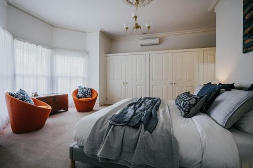 ein Schlafzimmer mit einem Bett und zwei orangefarbenen Stühlen in der Unterkunft The Duke of Queensberry in Daylesford