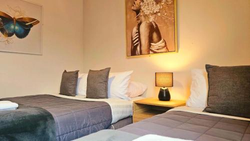 a bedroom with two beds and a lamp on a table at Wild Kea Lodge Franz Josef in Franz Josef