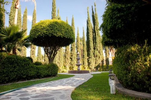 a garden with a pathway and trees and a fountain at Hotel El Dorado - cerca de Chapala y del Aeropuerto in Ixtlahuacán de los Membrillos