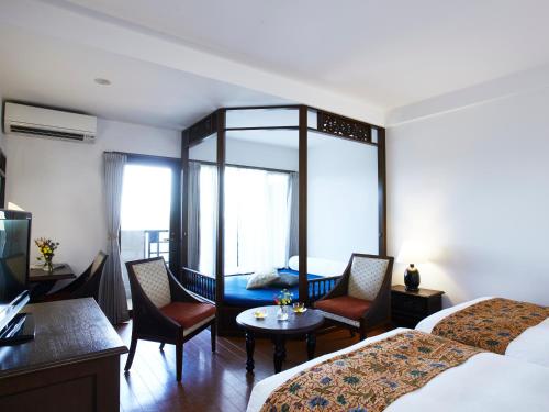 a hotel room with two beds and a table and chairs at Iriomote Hotel by Hoshino Resorts in Taketomi