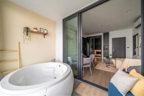 a bathroom with a tub and a living room at Vacaystation Edge Central Pattaya in Pattaya Central