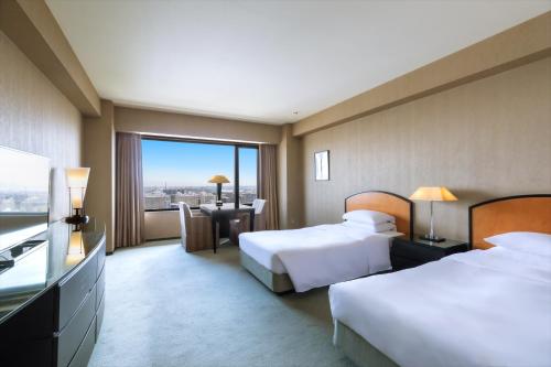 a hotel room with two beds and a desk with a view at RISONARE Osaka in Osaka