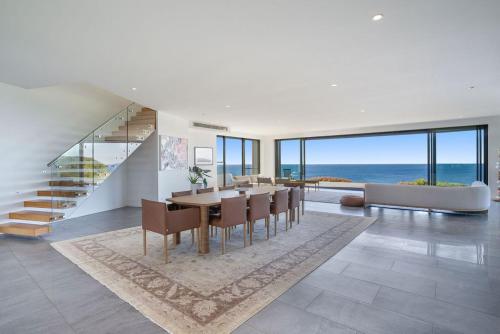 a dining room with a table and chairs and the ocean at Blue Seas in Lennox Head