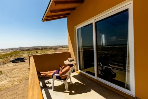 a woman sitting in a chair on the balcony of a house at Punta Ngritos wind & surf in Negritos