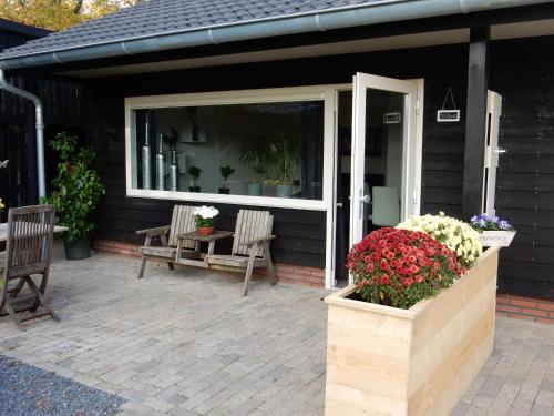 a screened in porch with chairs and flowers on it at De Rolders in Wapenveld