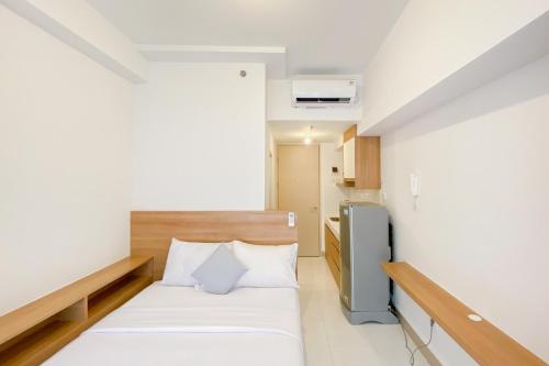 Kleines Zimmer mit einem Bett und einem Kühlschrank. in der Unterkunft Warm and Simply Look Studio Apartment at Tokyo Riverside PIK 2 By Travelio in Rawalembang