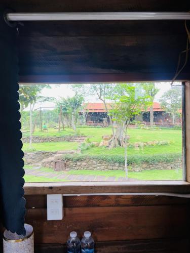 a window with a view of a park through it at Khu Nghỉ dưỡng Sinh thái Nhà Lụa Retreat in Ấp Quảng Giáo