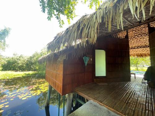 a thatched hut with a deck next to a body of water at Villa Baan Pak Pra in Ban Pak Pra (1)