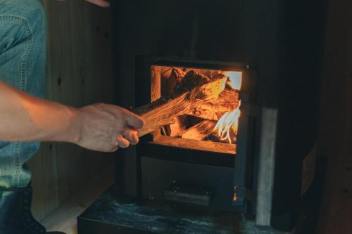a person is putting something into a fireplace at Earthboat Togakushi in Nagano
