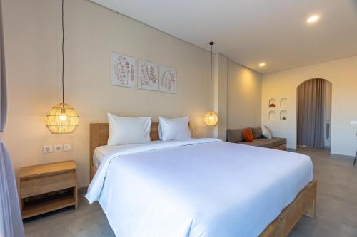 Un dormitorio con una gran cama blanca y luces. en Kelaya Guesthouse, en Sanur