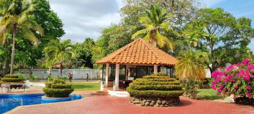 a gazebo in a garden with flowers and a pool at Mia Nueva Gorgona in Nueva Gorgona