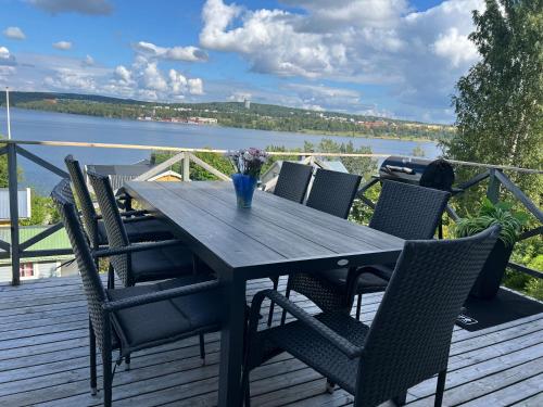 a wooden table and chairs on a deck with a view of the water at Villa LakePlats in Östersund