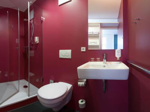 a red bathroom with a toilet and a sink at mk hotel berlin in Berlin