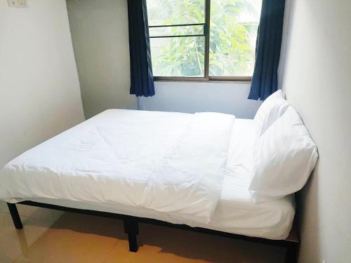 a bed with white sheets in a room with a window at X Mitr Inn Nimman มิตร อินน์ นิมมาน 12 in Chiang Mai