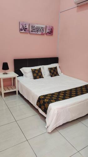 a bedroom with a large white bed and a table at Homestay Ar-Rayyan in Pokok Sena