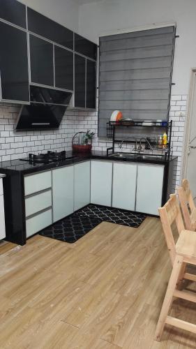 a kitchen with black and white cabinets and a wooden floor at Homestay Ar-Rayyan in Pokok Sena