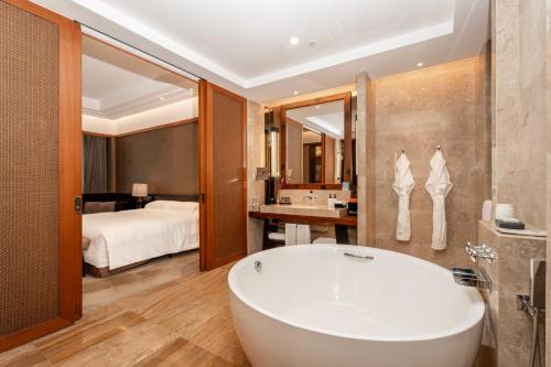 a bathroom with a bath tub and a bedroom at InterContinental Kunming by IHG in Kunming