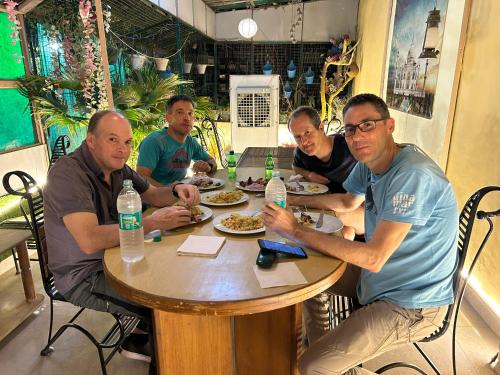 a group of men sitting at a table eating food at Max Guest House in Agra