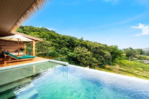 a swimming pool in front of a house with trees at Wild Cottages Elephant Sanctuary Resort in Amphoe Koh Samui
